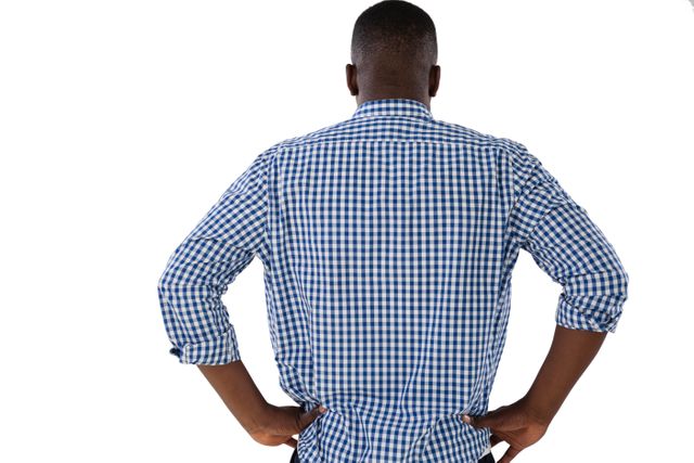 Man standing with hands on hips in a checkered shirt, viewed from the back. Useful for concepts related to confidence, casual fashion, posture, and decision-making. Ideal for advertisements, lifestyle blogs, and fashion articles.