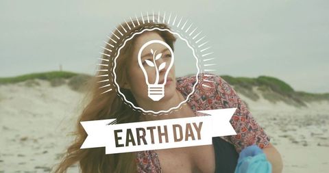 Volunteer celebrating earth day cleaning beach holding blue glove with windblown hair