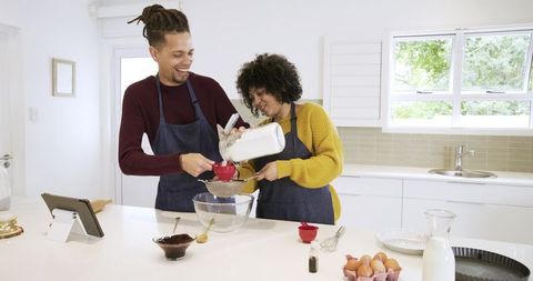 African american couple sifting flour while baking in bright sunlit modern kitchen
