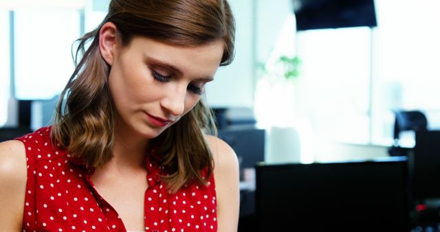 Focused young businesswoman in red polka dot blouse at workspace - Download Free Stock Images Pikwizard.com