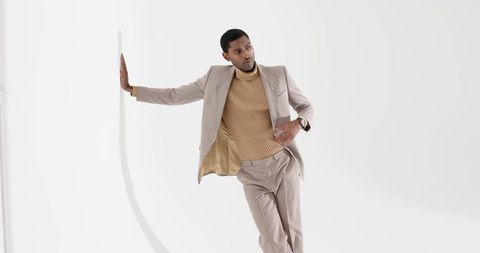 Stylishly Dressed Man Leaning Against Modern White Panel