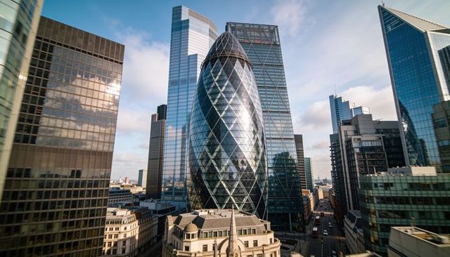 Gherkin skyscraper reflecting glass towers in london financial district skyline at sunrise