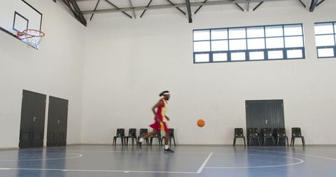 Focused african american athlete dribbling basketball indoors