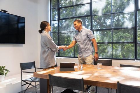 Coworkers Shaking Hands in Bright Modern Meeting Room