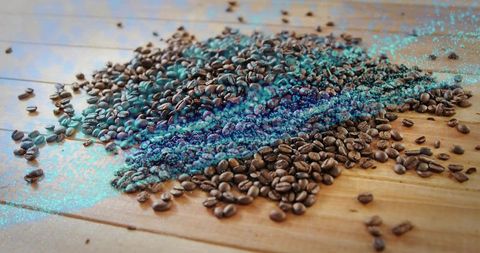 Roasted coffee beans scattering with turquoise digital particles on wooden tabletop