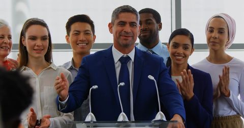 Successful business leader celebrating achievement with team at seminar podium