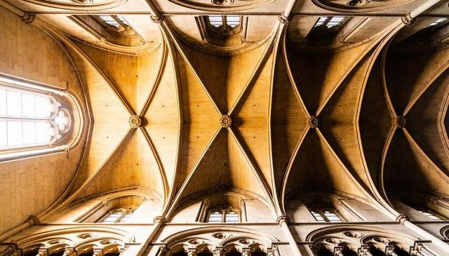 Capturing golden gothic ribbed vaults over symmetrical cathedral nave ceiling