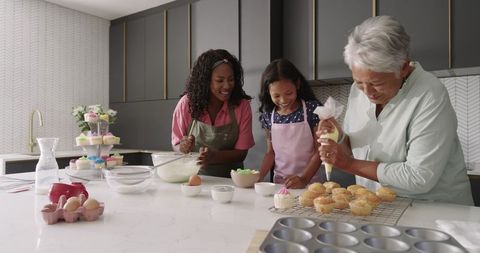 Diverse multigenerational family decorating cupcakes on bright modern kitchen island