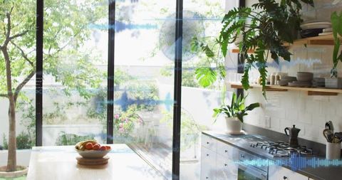 Sunlit modern kitchen opening onto lush garden with island and indoor plants
