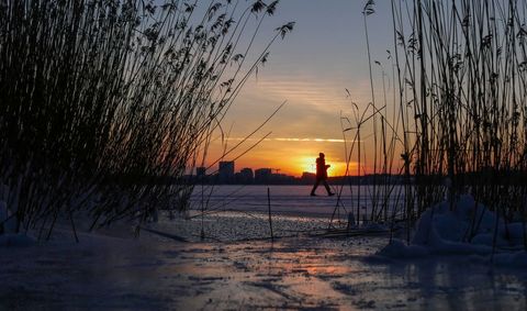 Silhouetted Figure Walks on Frozen Lake at Sunset