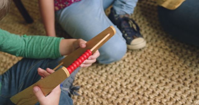 Children engaged with an educational counting toy, promoting development and learning. Setting suggests a cozy indoor environment with a textured rug, denim jeans, and casual shoes. Ideal for use in educational materials, parenting blogs, and toy advertisements focusing on learning and developmental activities for kids.
