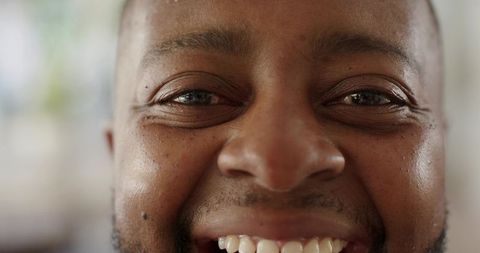 Closeup smiling man showing skin texture, stubble, mole, warm natural window light
