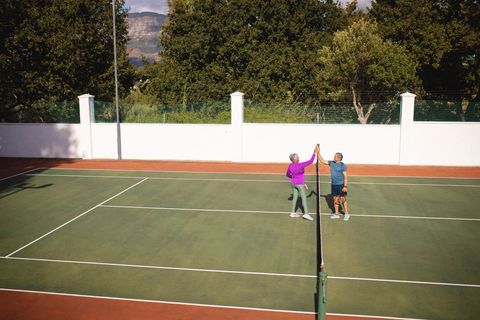 Senior Couple Celebrating Victory on Tennis Court With High-Five