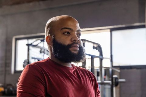 African american man standing resting between sets in industrial gym with cable machine