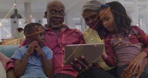 Multigenerational family watching tablet together on couch sharing moments and learning