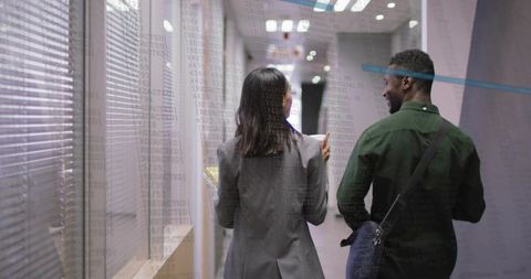 Professionals Collaborating While Walking Through Office Hallway