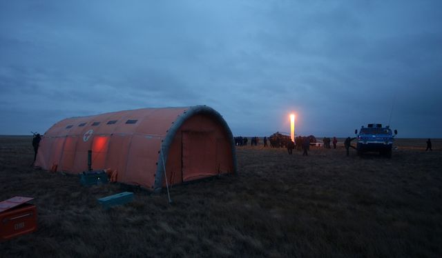 An inflatable medical tent stands in the foreground of the Expedition 9 landing site, while in the background the Soyuz capsule lays on its side after landing approximately 85 kilometers northeast of Arkalyk in northern Kazakhstan with Expedition 9 crew members Flight Engineer Michael Fincke, Commander Gennady Padalka and Russian Space Forces cosmonaut Yuri Shargin, Sunday, October 24, 2004.