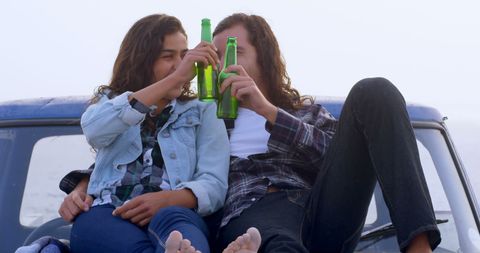 Couple Relaxing on Car Roof with Drinks by the Ocean