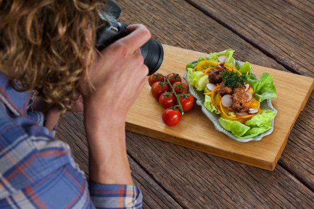 Close-up of photographer clicking a picture of food using digital camera in studio