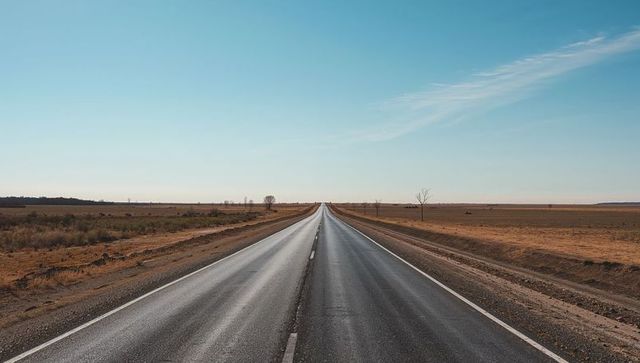 Endless asphalt: straight two-lane highway stretching toward horizon across arid plains
