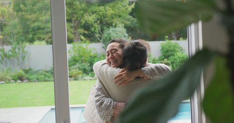 Happy Mother and Daughter Embracing by Garden Window