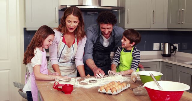 A cheerful moment in a modern kitchen where a family of four, consisting of parents and their two young children, is kneading dough on a kitchen island. The counter is scattered with flour, baking tools, and ingredients. This image is great for themes related to family time, cooking activities, cooperative labs, advertisement for kitchen utensils, articles about parenting or creating homemade meals, and lifestyle blogs promoting quality family bonding moments.