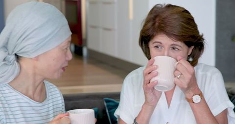 Senior multiracial friends sharing coffee in comforting living room chat