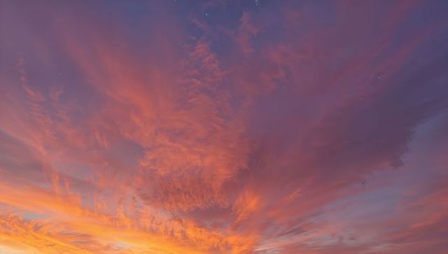 Pastel sunset clouds radiating warm horizon glow with wispy streaks and twilight hues