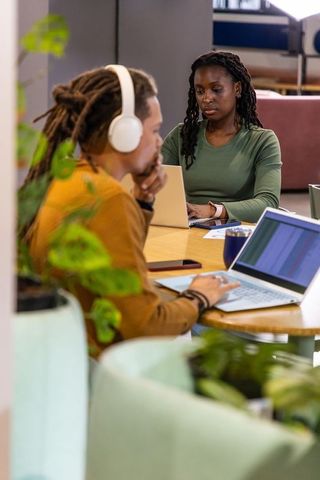 African American Coworkers Working in Modern Coworking Lounge with Laptops and Plants
