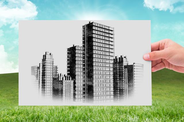 Hand holding detailed drawing of urban skyline with green field and clear sky in the background. Suitable for use in creative works, urban planning, architecture presentations, environmental and sustainability concepts.