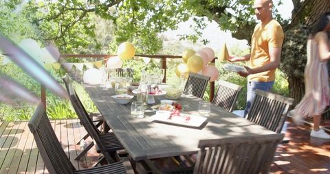 Hosting sunlit backyard party with pastel balloons and wooden outdoor dining table