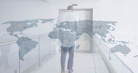 Mature doctor walking hospital corridor with world map overlay for global healthcare