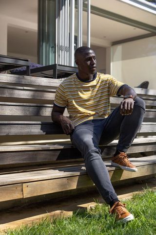 Stylish man showcasing watch on modern deck in sunny urban setting