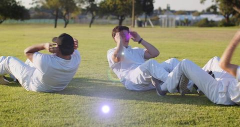 Sunlit Outdoor Team Training Doing Sit-Ups on Grass in White Uniforms