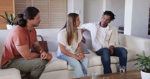 Friends in serious discussion on couch expressing support and comfort
