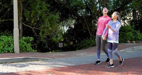 Mother and Daughter Enjoy Walking Together in Sunlit Park