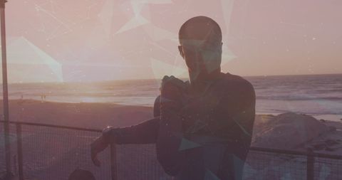 Silhouette of Man Stretching on Beach at Sunset with Digital Overlay