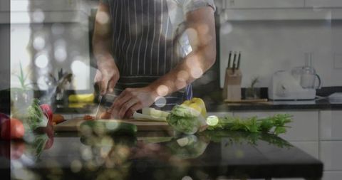 Man slicing fresh vegetables on wooden board in modern kitchen with glossy reflections