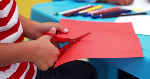 Cute little boy cutting paper shapes classroom in playschool