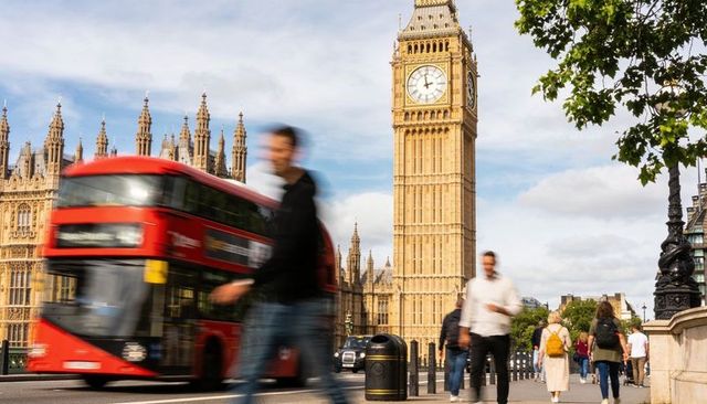 Motion-blurred red double-decker passing elizabeth tower with palace of westminster spires