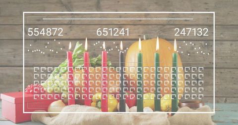 Kwanzaa kinara with seven lit candles and harvest centerpiece on rustic wooden table