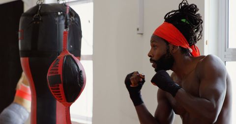 Intense Boxer Training Focuses on Punch Bag in Fitness Studio