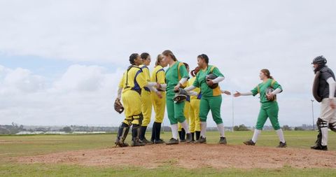 Female softball players celebrating on pitcher's mound