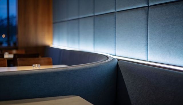 Curved slate blue banquette with quilted wall panels and modern ambient led strip lighting