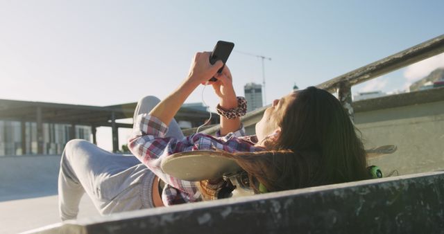 Teenage Girl Lying on Skateboard in Sunny Skate Park Using Smartphone - Download Free Stock Images Pikwizard.com