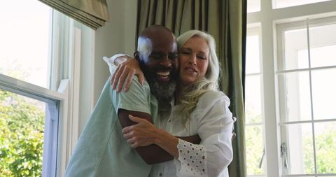 Interracial Senior Couple Embracing with Joyful Expression Indoors