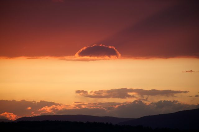 Vivid sunset scene with mountains and clouds on horizon. Perfect for use in travel brochures, outdoor adventure promotions, nature calendars, and home decor prints.