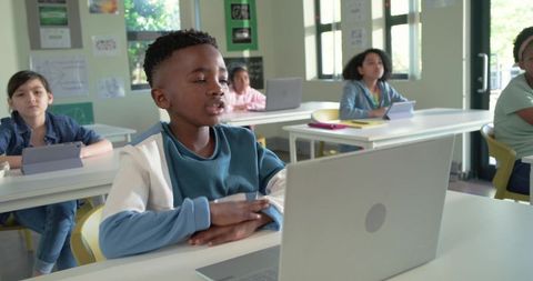 African American Boy Using Laptop in Bright Classroom Engaging in Virtual Learning