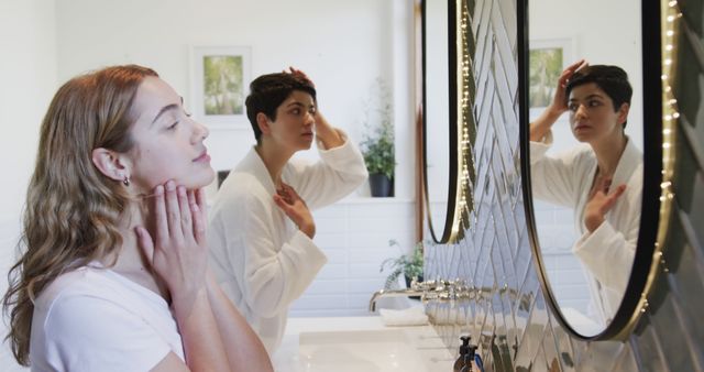 Two women performing skincare routines at bathroom mirror - Download Free Stock Images Pikwizard.com