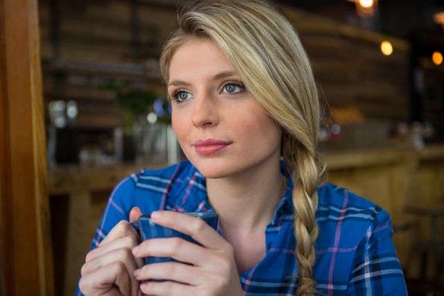 Close-up of thoughtful young woman having coffee in cafeteria